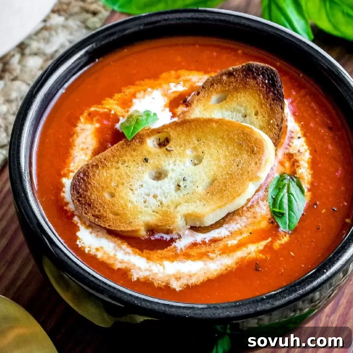 Roasted Red Pepper Soup in a black bowl, garnished with cream