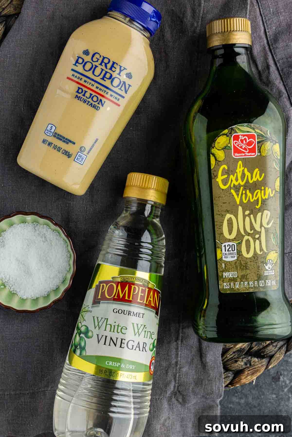 Ingredients for a homemade vinaigrette dressing including olive oil, white wine vinegar, Dijon mustard, and salt.