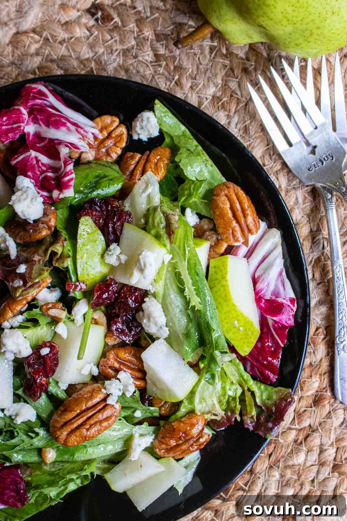 A black plate showcasing the perfectly plated winter salad, ready to be enjoyed with forks.