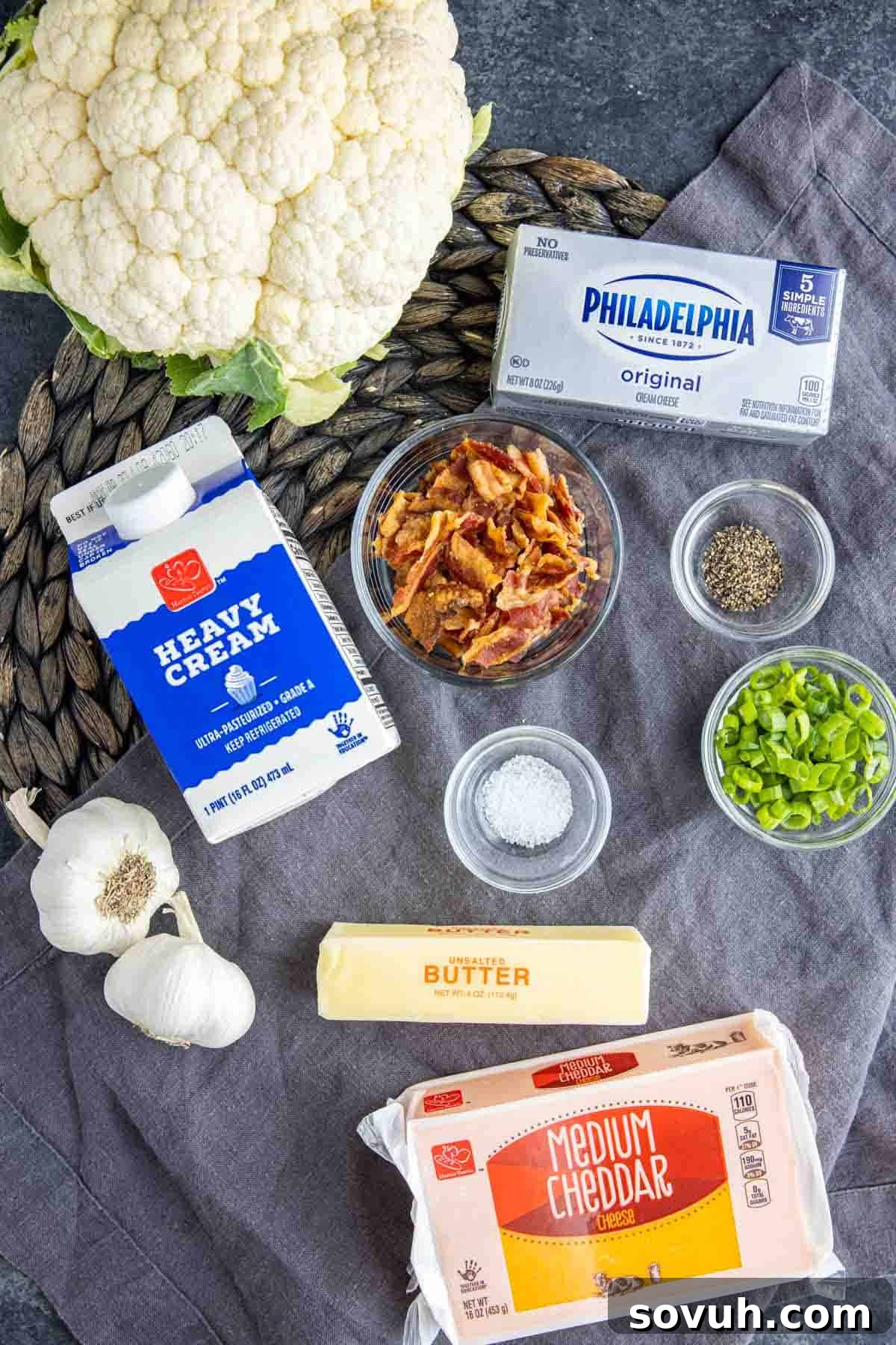 Ingredients laid out for Baked Cauliflower with Cheese Casserole, including cheeses, heavy cream, and cauliflower