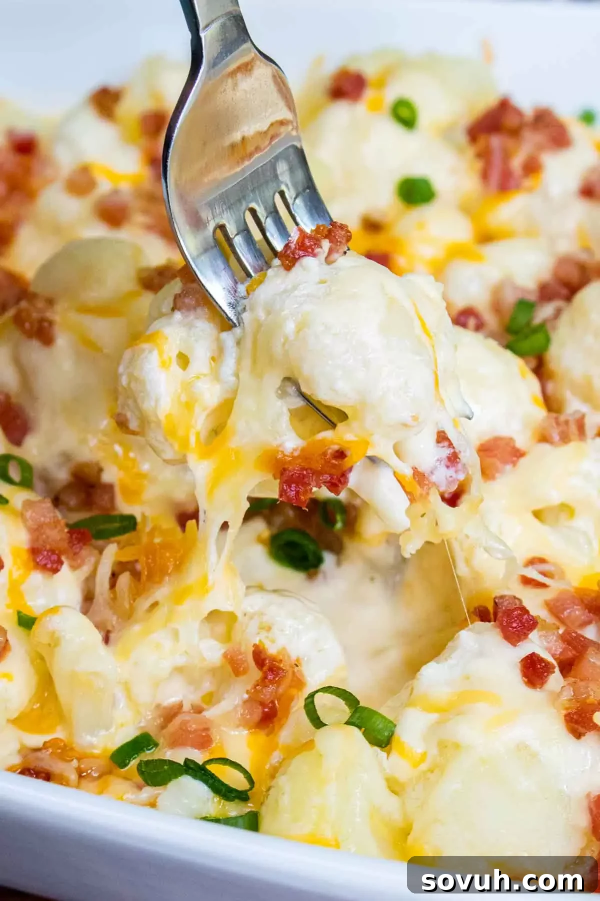 A serving of Baked Cauliflower with Cheese Casserole on a fork, showing the creamy texture
