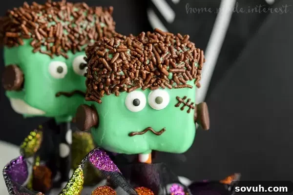 Close-up of a Frankenstein Marshmallow Pop, showcasing its green candy coating, chocolate sprinkle hair, and sweet candy eyes.