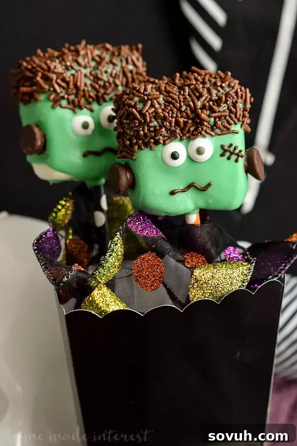 A collection of finished Frankenstein Marshmallow Pops arranged vertically, ready for a Halloween party.