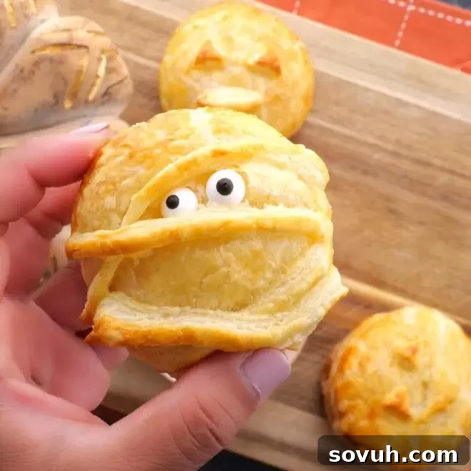 Close-up of a golden Halloween Baked Cheese mummy with edible eyes, ready for a spooky party.