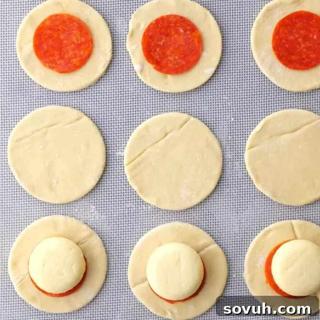 A 3-inch round cookie cutter being used to cut circles from a sheet of puff pastry.