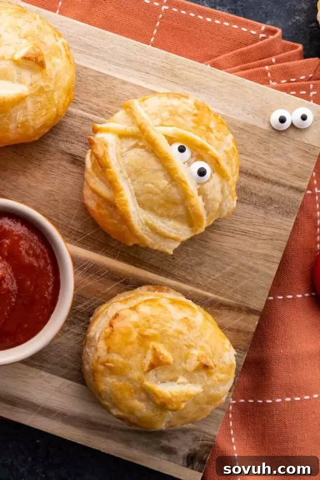 Halloween Baked Cheese platter featuring both mummy and pumpkin designs, garnished for a festive look.