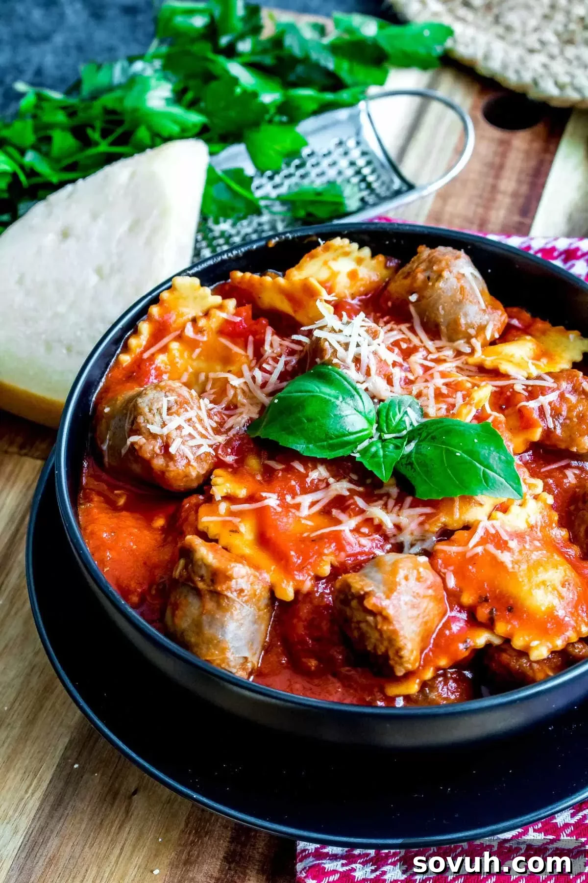 A close-up of a serving of Ravioli and Sausage Slow Cooker Casserole in a black bowl, ready to be enjoyed.