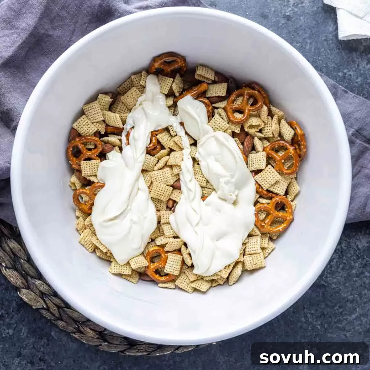 Tossing Bunny Bait ingredients to coat with white chocolate in a bowl