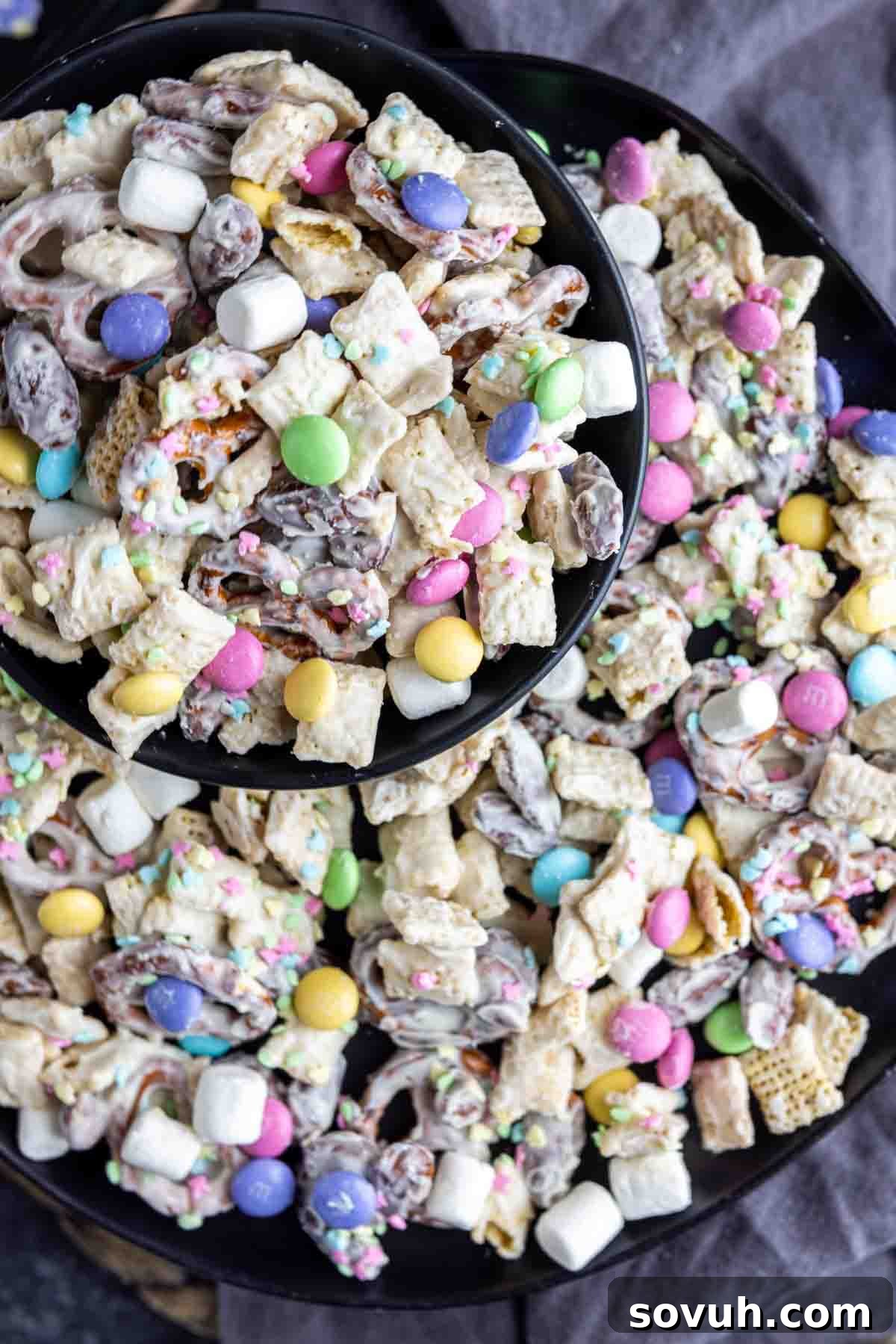 A black bowl and platter filled with colorful Bunny Bait snack mix