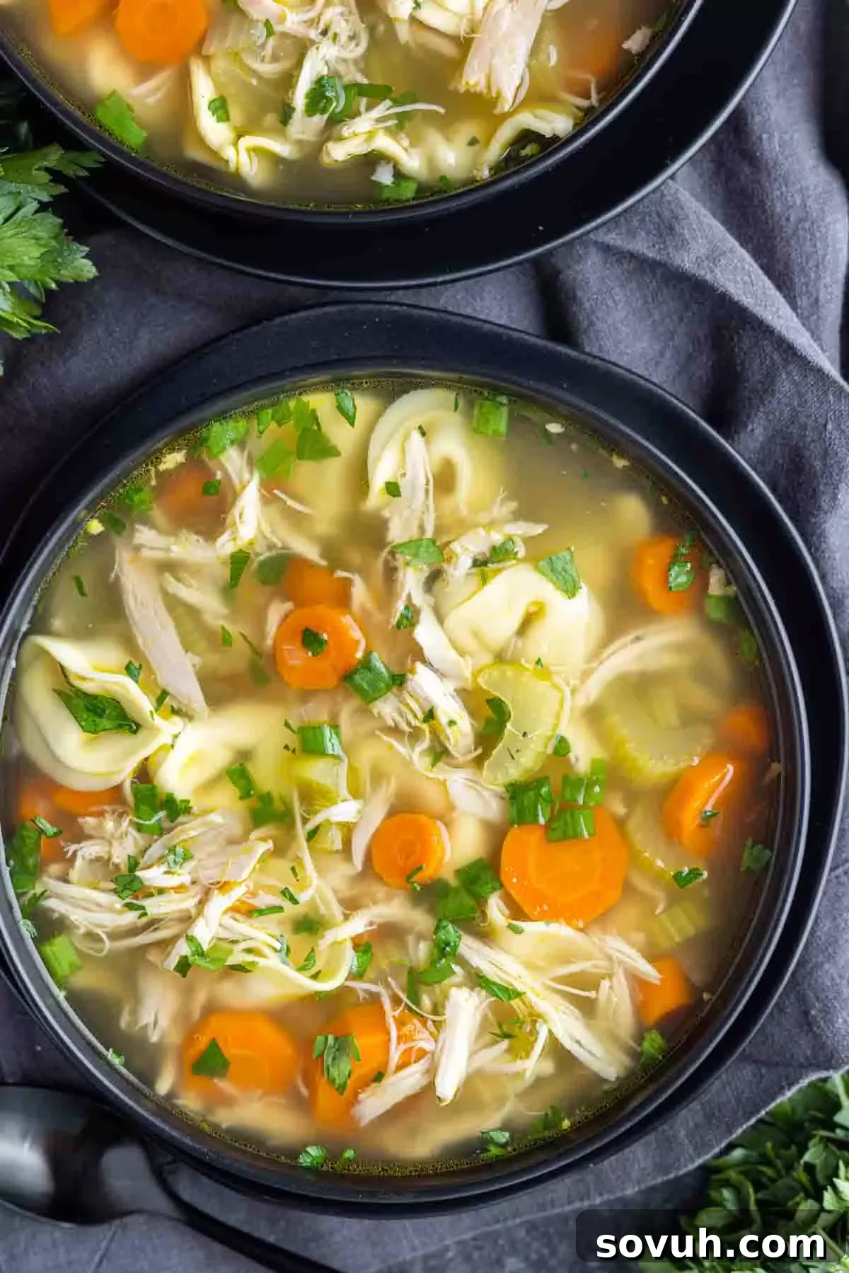 A black bowl filled with Rotisserie Chicken Soup with Tortellini, ready to eat