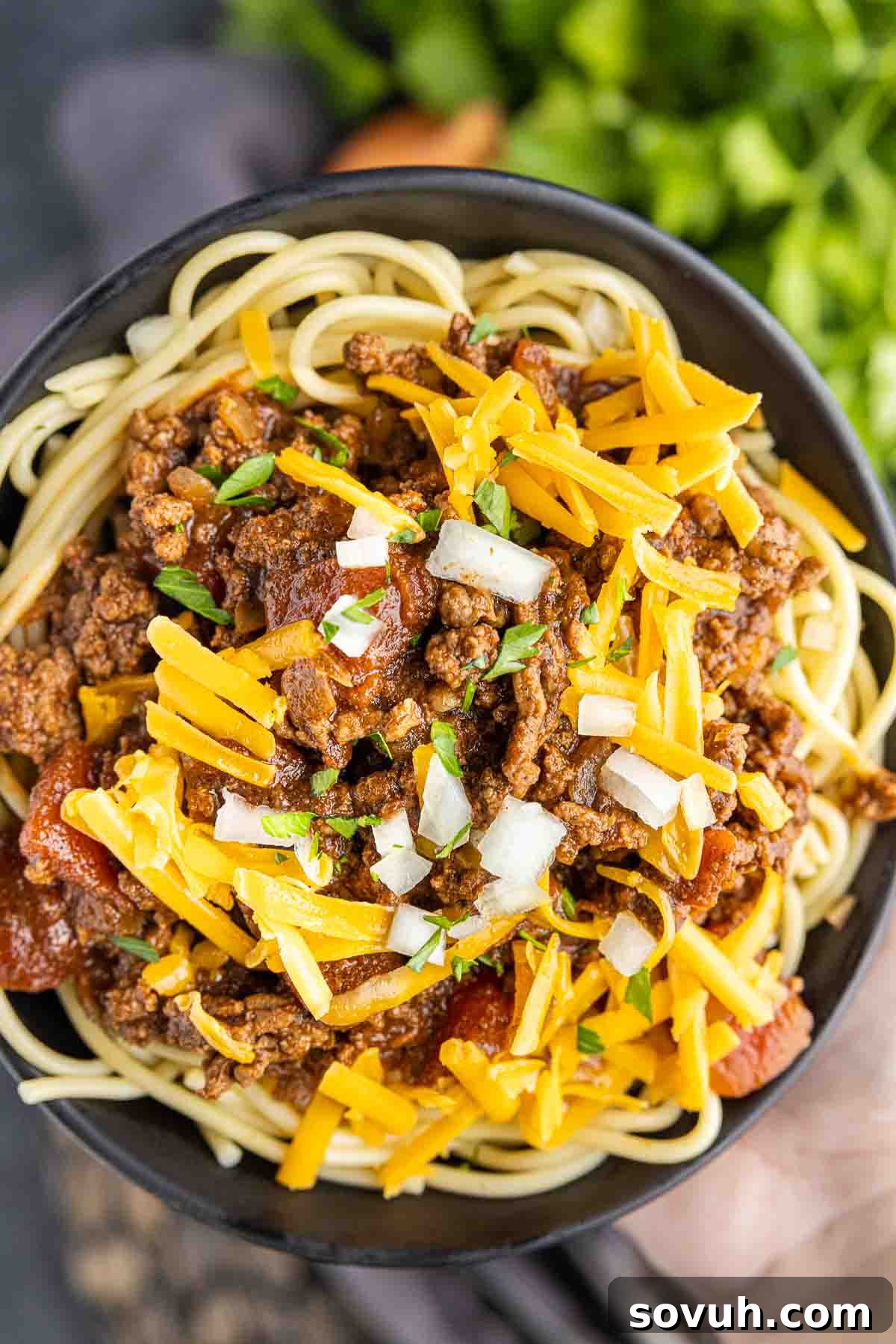 bowl of Cincinnati Chili topped with raw onions and shredded cheese