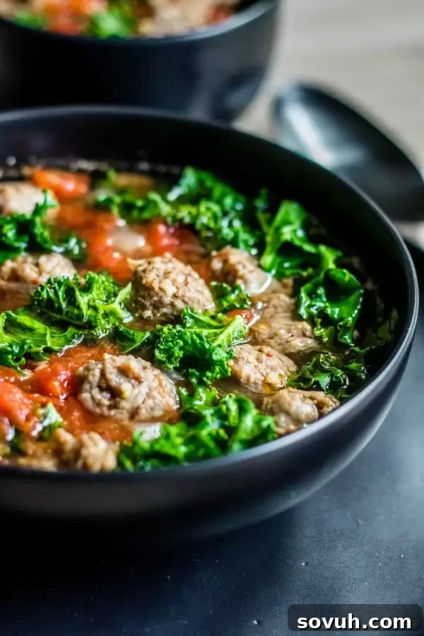 Hearty low carb soup with Italian sausage and fresh kale, vertical shot
