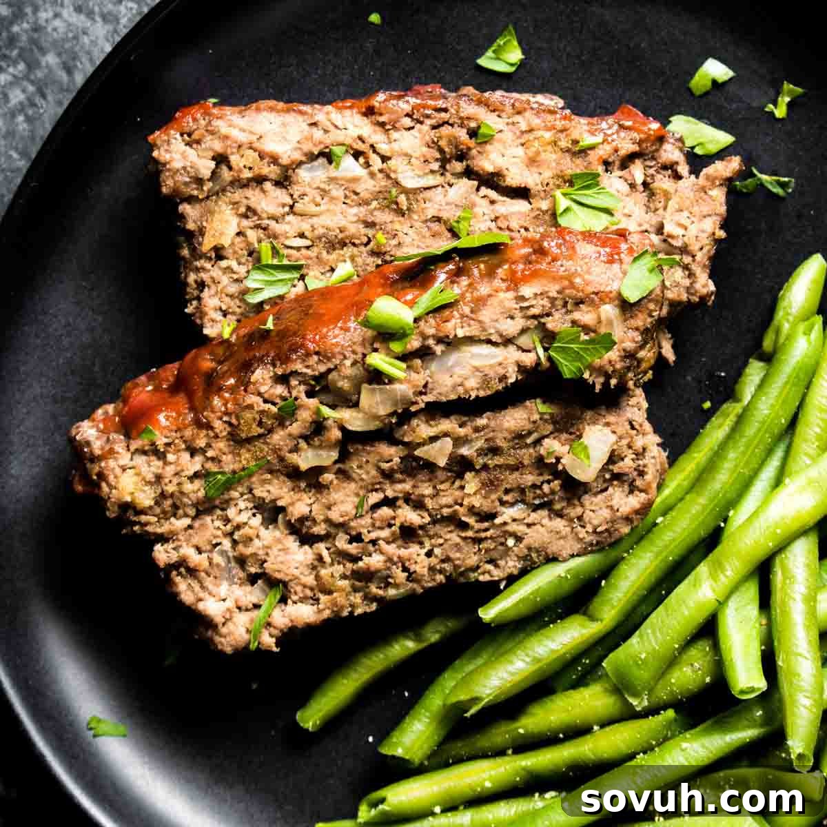 Keto Meatloaf and green beans on a black plate.