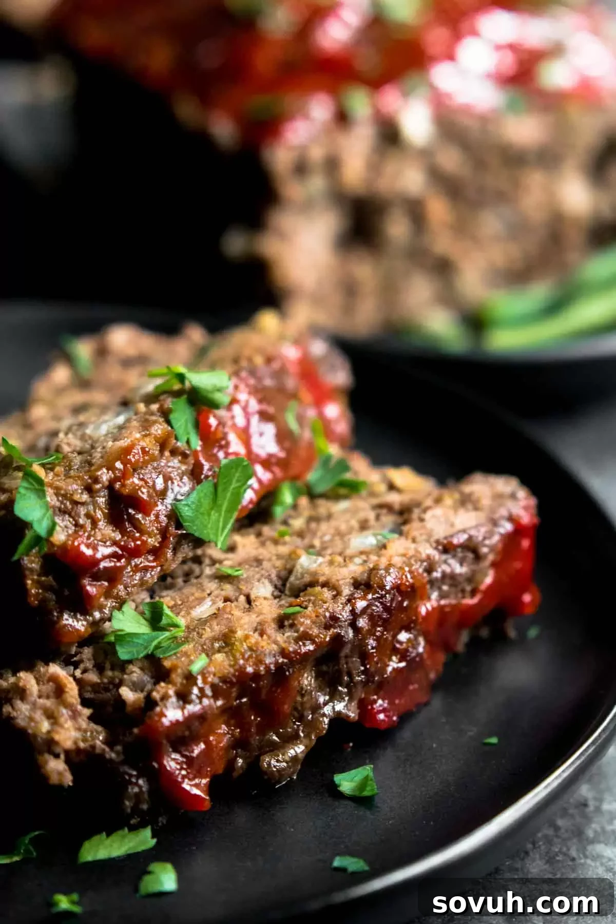 A slice of keto meatloaf on a black plate.