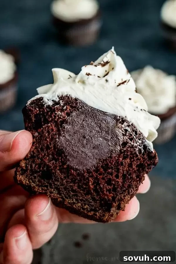 Close-up of a cupcake being filled with dark chocolate ganache.