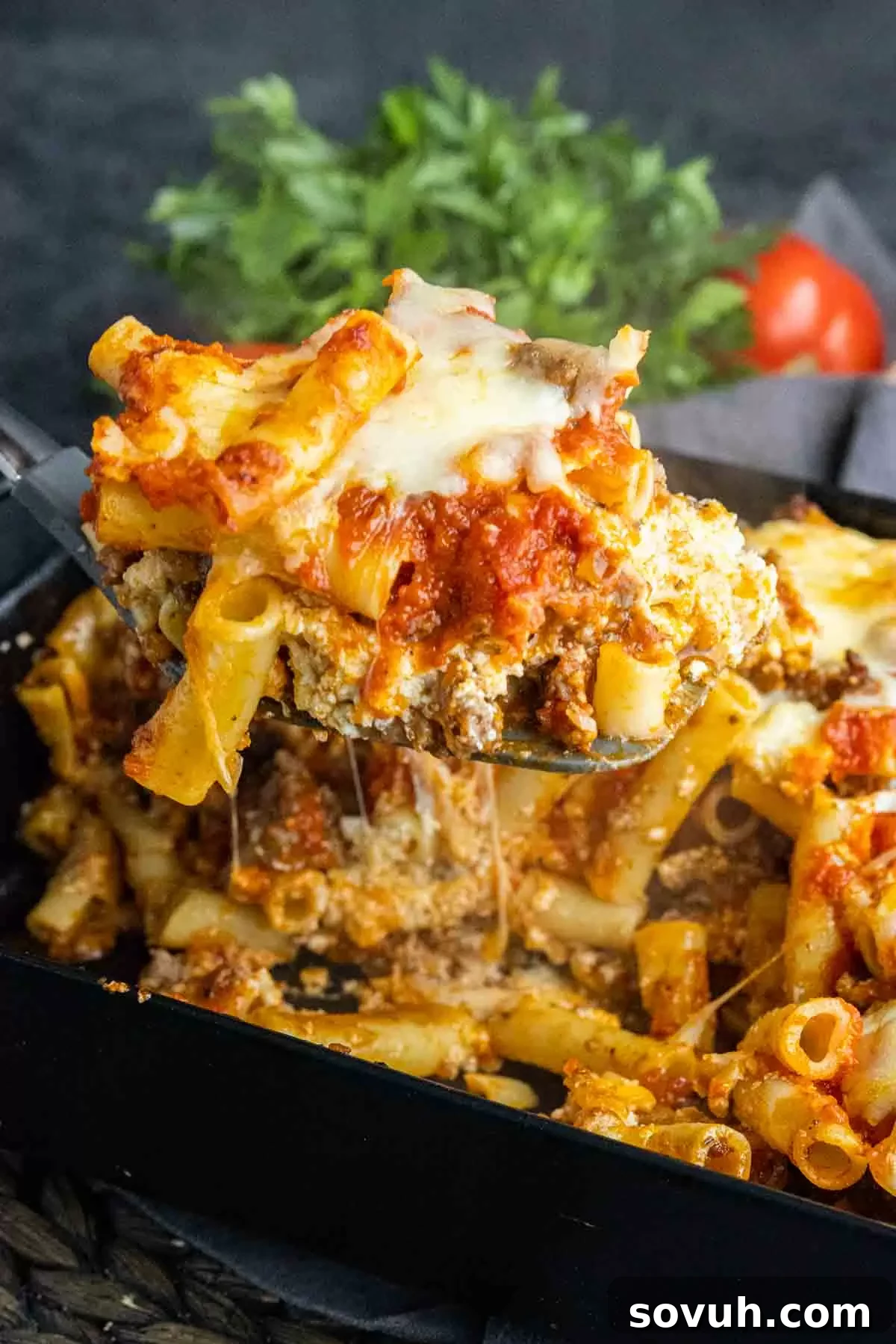 A serving of Sausage Baked Ziti on a white plate, highlighting the melted cheese and rich sauce.