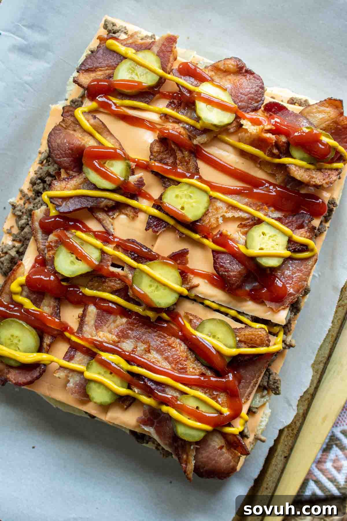 Bacon Cheeseburger Sliders on a platter, ready to be served, accompanied by small bowls of ketchup, mustard, and extra pickles
