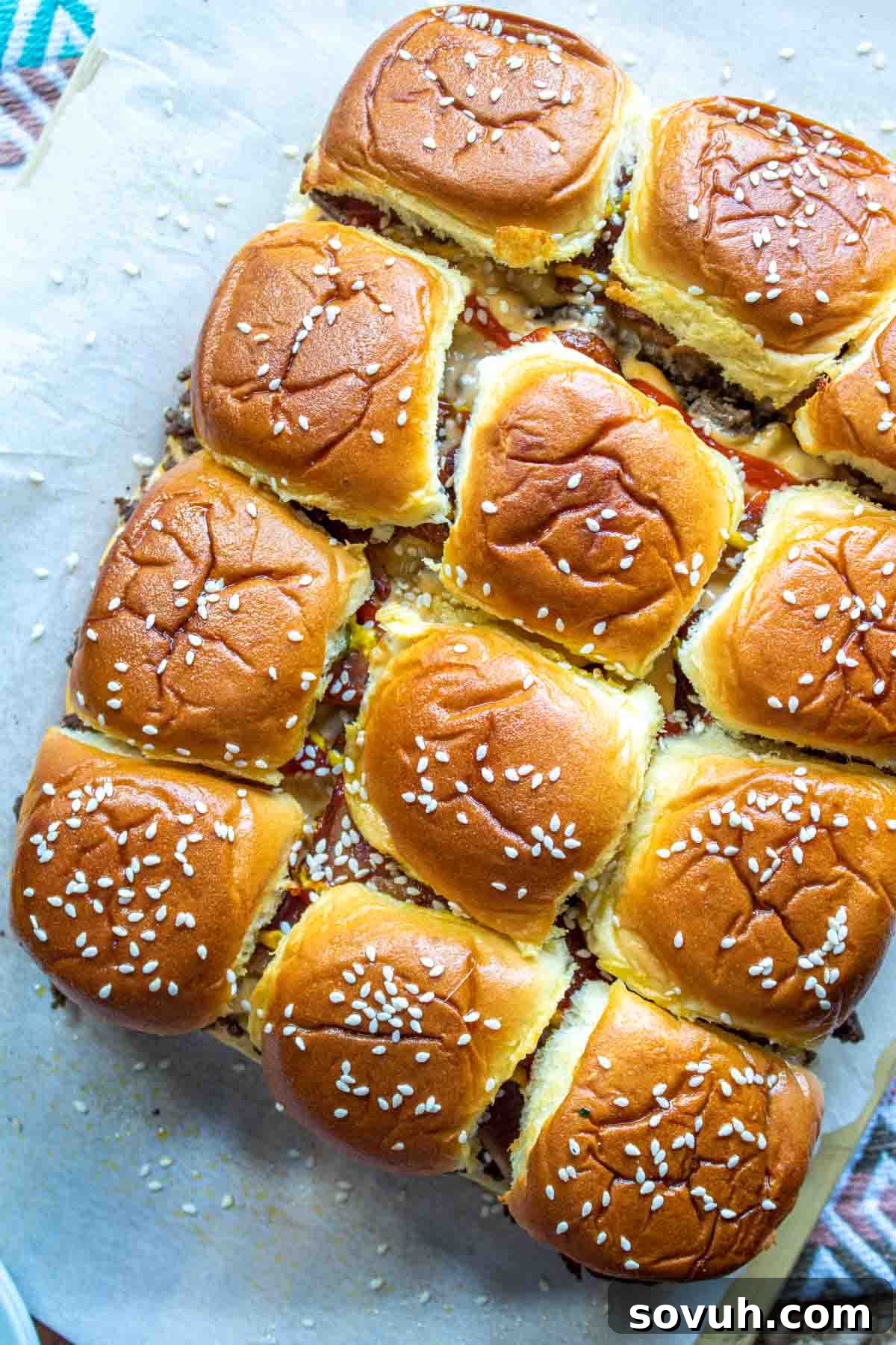 Freshly baked Bacon Cheeseburger Sliders, glistening with melted butter and sprinkled with sesame seeds