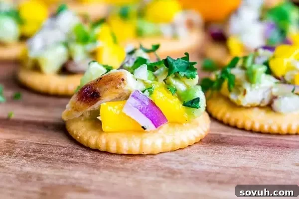 Mango Chicken Salad on a RITZ cracker, garnished with fresh cilantro, avocado, and mango