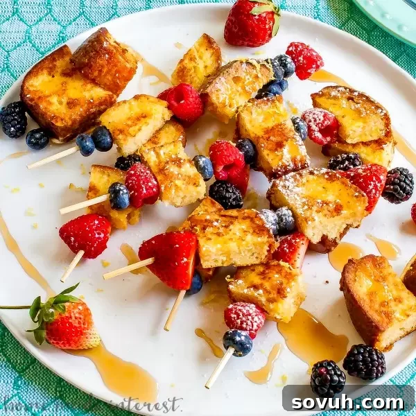Lemon poundcake french toast skewers on a white plate with powdered sugar and fresh berries