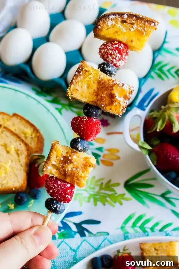 lemon pound cake french toast with fresh berries on a skewer, garnished with powdered sugar