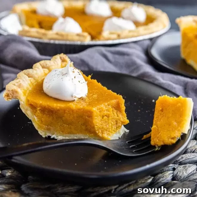 A comforting slice of Sweet Potato Pie served on a black plate with a fork, ready to be enjoyed.