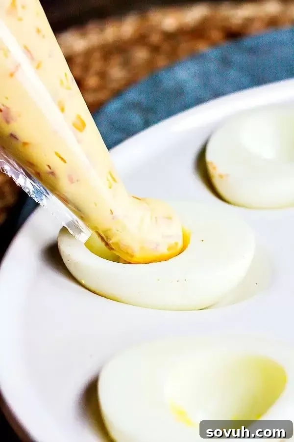Piping the creamy Mississippi Sin deviled egg filling into egg white halves, a step-by-step image
