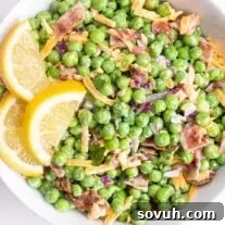 Velvety Spring Pea Salad 11 a white bowl of english pea salad garnished with fresh lemon slices