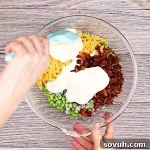 Velvety Spring Pea Salad 15 mixing the dressing into the english pea salad in a glass bowl