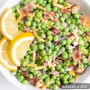 Velvety Spring Pea Salad 16 a white bowl of english pea salad garnished with fresh lemon slices