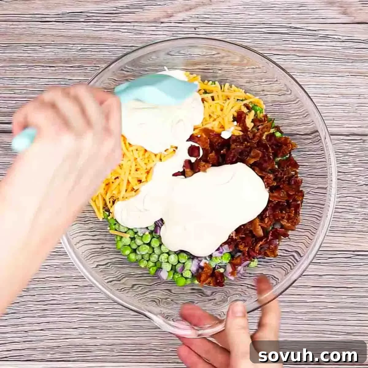 Velvety Spring Pea Salad 8 mixing the dressing into the english pea salad in a glass bowl