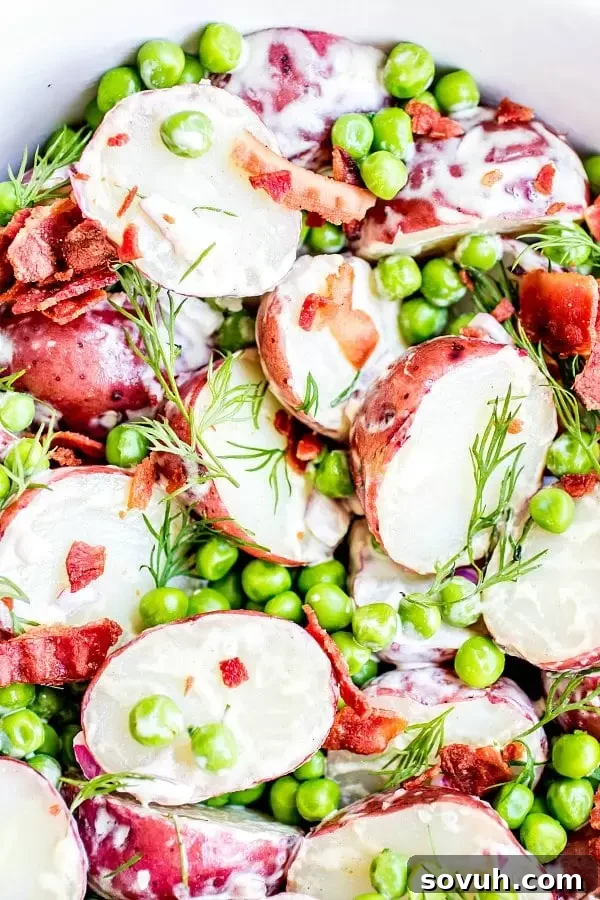 English Pea and Potato Salad with large crumbles of bacon, bright green peas, and creamy vinaigrette on red potatoes