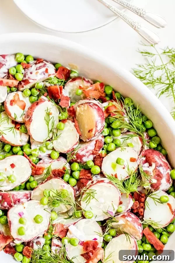 English Pea and Potato Salad in a large white bowl with sprigs of dill.