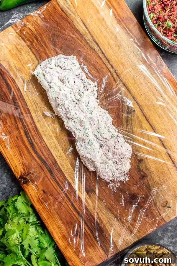 Scooping goat cheese mixture onto plastic wrap to form a log.