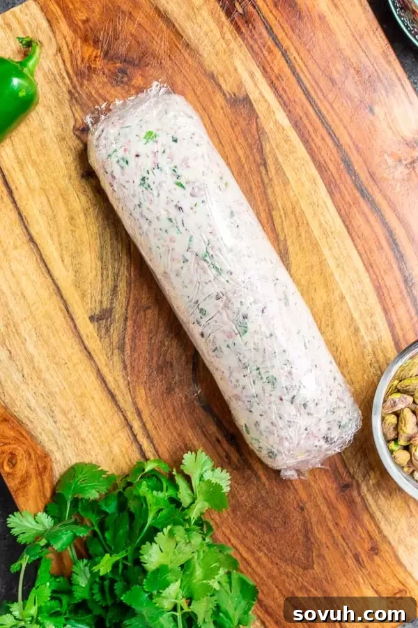 Goat cheese mixture rolled tightly in plastic wrap to create a smooth, cylindrical log.