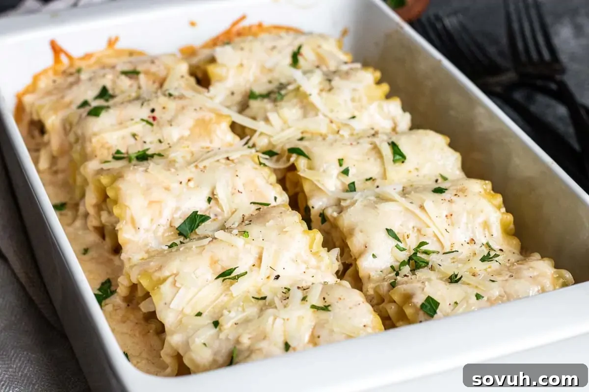 Baked pasta rolls in a white dish, topped with melted cheese and sprinkled with chopped herbs. Black forks are visible in the background.