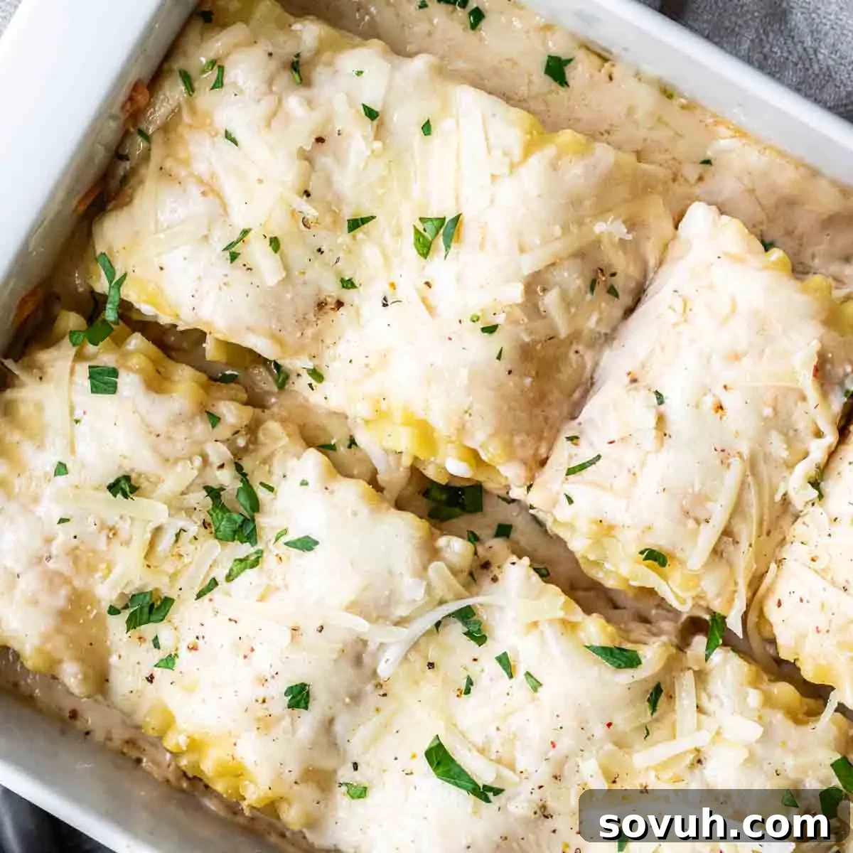 A baking dish filled with cooked lasagna, topped with melted cheese and sprinkled with chopped parsley.