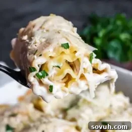 A fork holding a creamy, cheese-filled pasta roll, garnished with herbs.