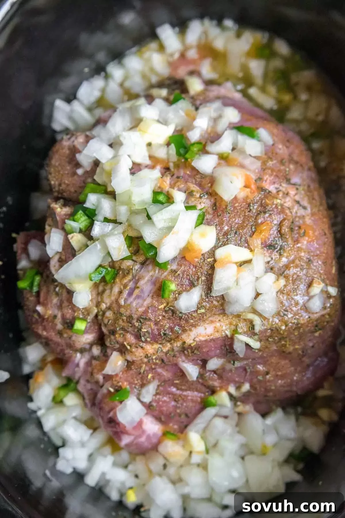 Pork shoulder seasoned with spices and aromatics in a slow cooker, ready for cooking