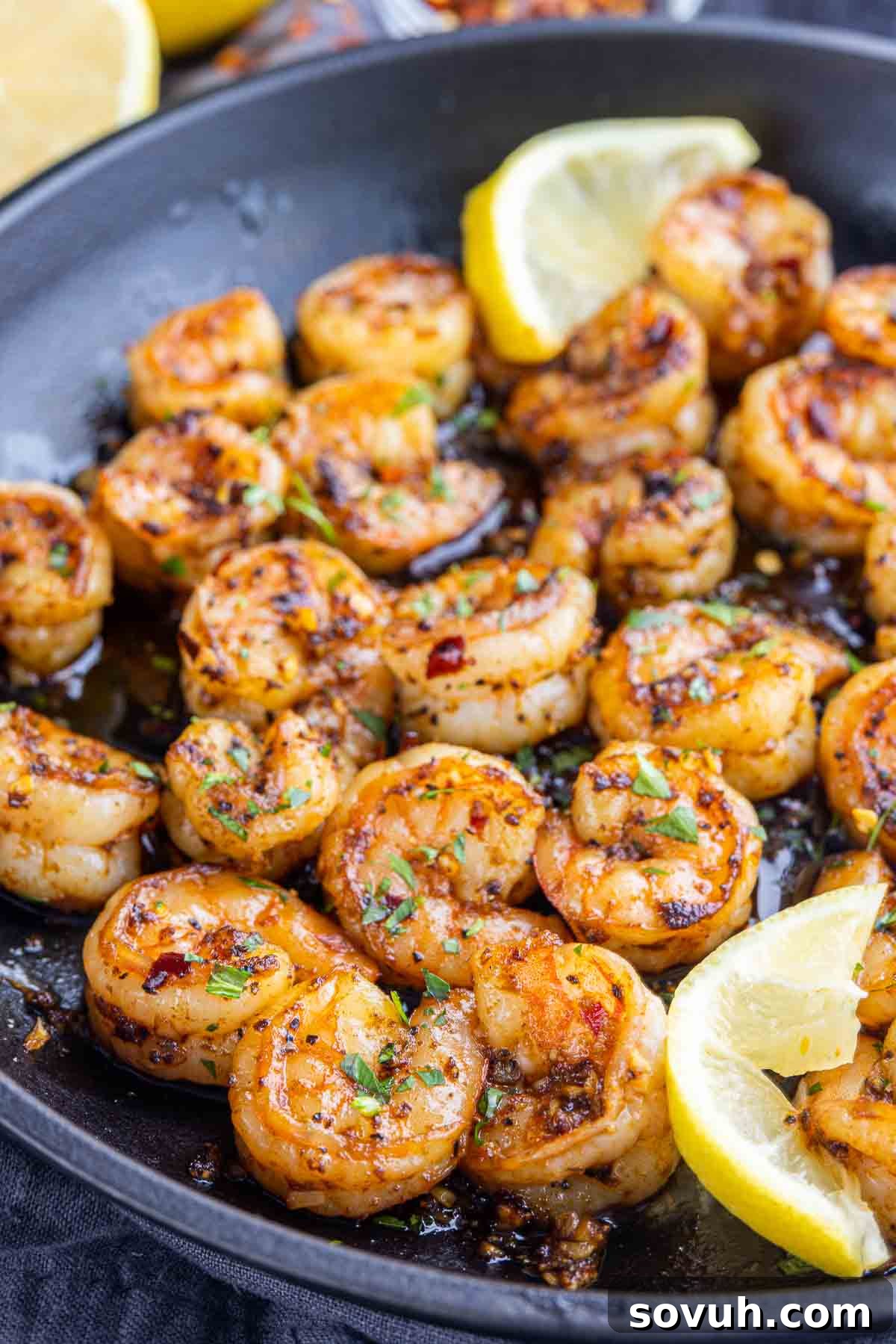 Sizzling Chili Garlic Shrimp 6 Gambas Pil Pil simmering in a skillet with lemon wedges, ready to be served.