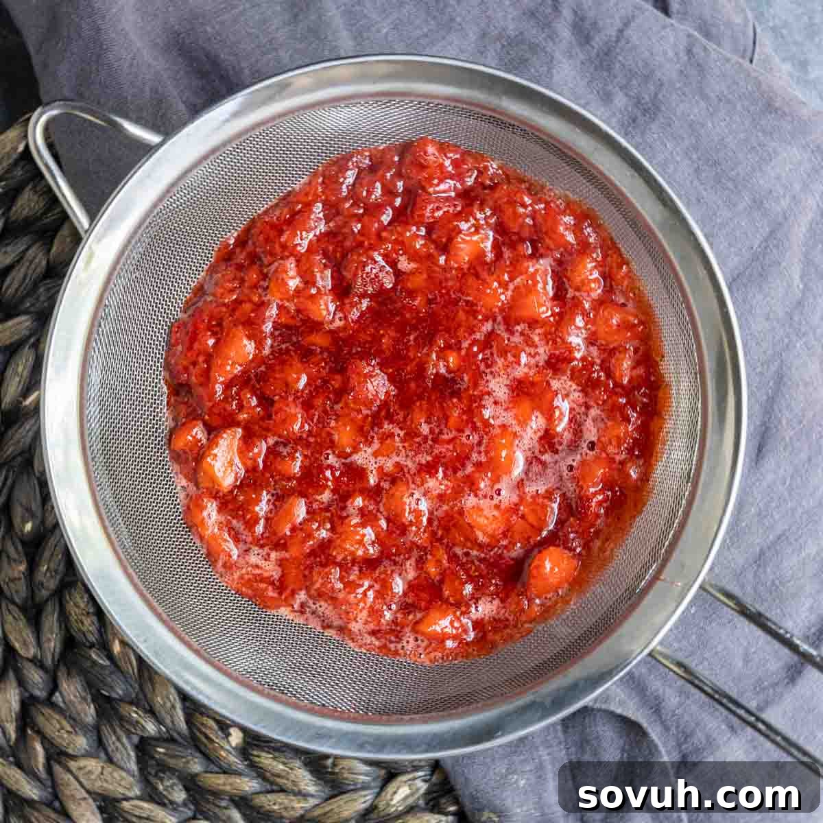 Straining Strawberry Coulis through a fine-mesh strainer