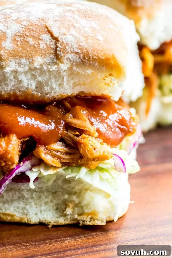 Smoky Pulled Jackfruit Sliders 5 A close-up shot of homemade BBQ Jackfruit Sliders on a rustic wooden board, accompanied by a small bowl of savory homemade BBQ sauce, showcasing their irresistible appeal