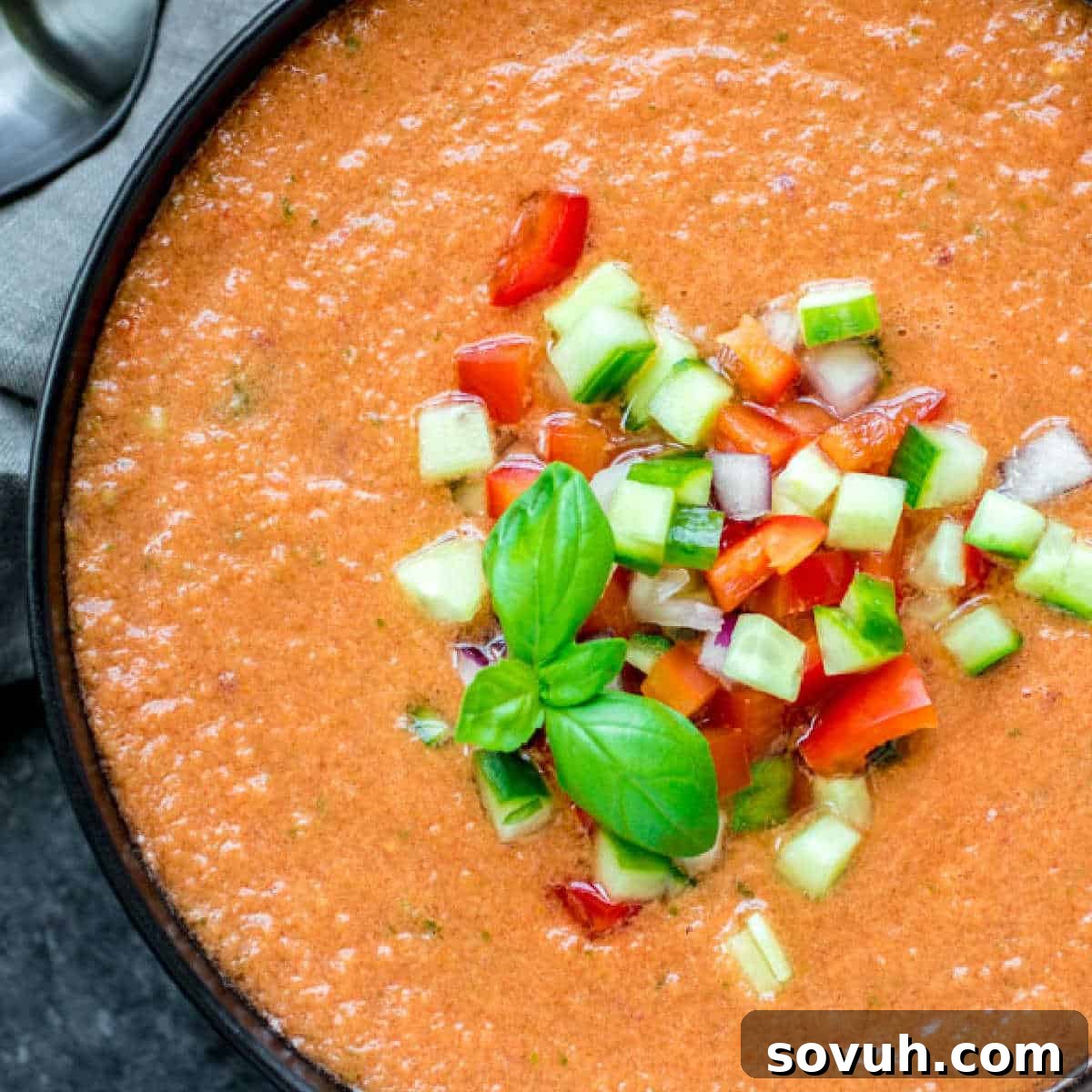 A beautifully presented bowl of homemade Gazpacho Soup, garnished with finely chopped fresh vegetables like tomatoes, cucumbers, and bell peppers, ready to be enjoyed as a refreshing summer dish.
