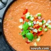 A vibrant bowl of Gazpacho Soup, beautifully garnished with fresh diced vegetables and a hint of olive oil, showcasing its appetizing appeal.