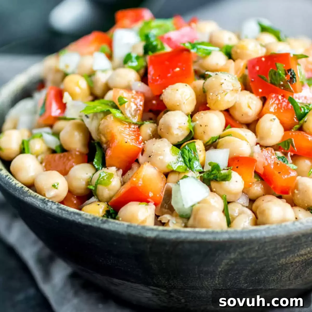 A vibrant bowl of Mediterranean Chickpea Salad (Salada de Grão de Bico) ready to be served, garnished with fresh herbs
