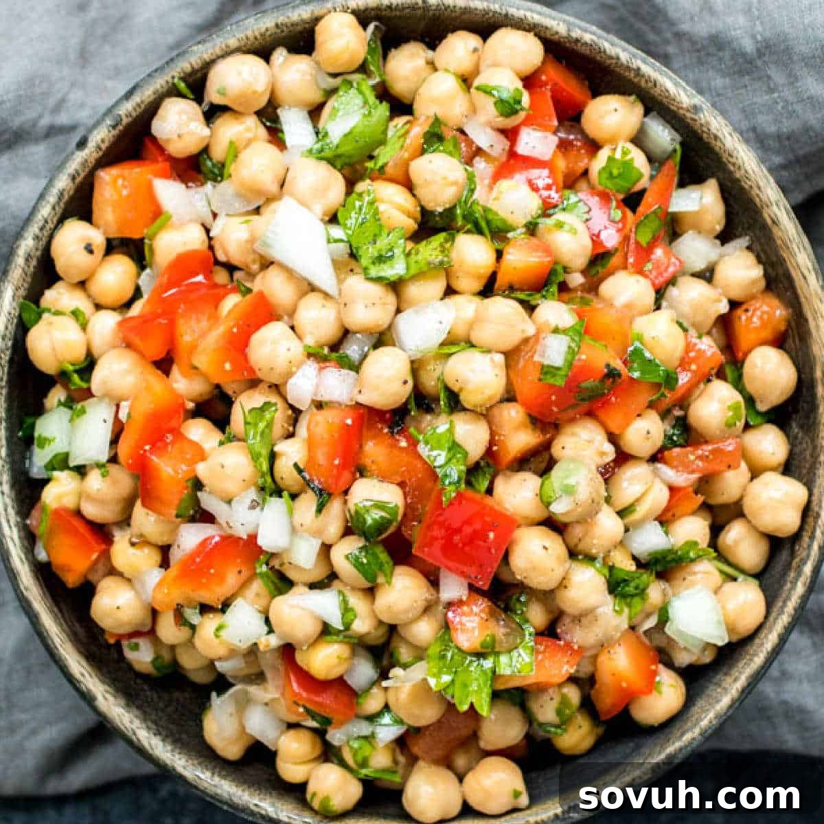 A rustic wooden bowl brimming with Mediterranean Chickpea Salad, beautifully garnished with fresh parsley and ready for a healthy meal