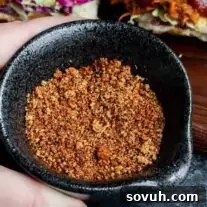 The Ultimate Memphis Dry Rub 6 A hand holding a black bowl filled with a Memphis Dry Rub