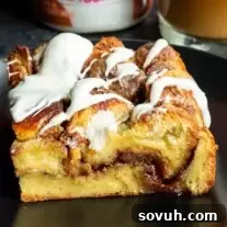 A piece of cinnamon roll casserole with icing on a plate.