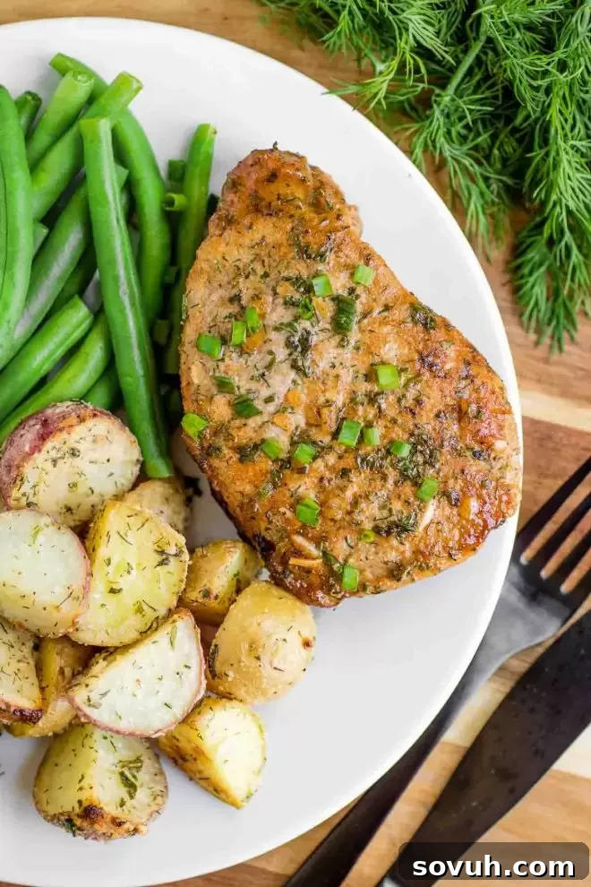 Baked Ranch Pork Chops presented beautifully on a white plate with roasted potatoes and green beans