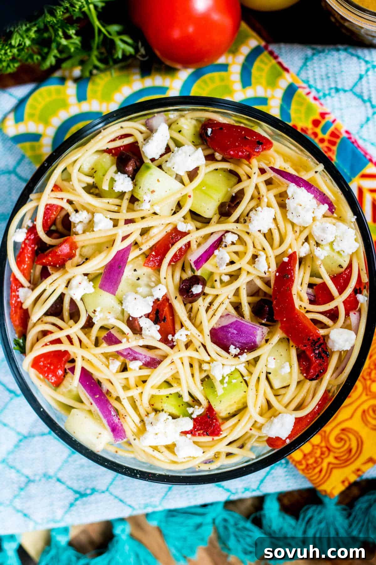 Greek Spaghetti Salad in bowl with colorful towels